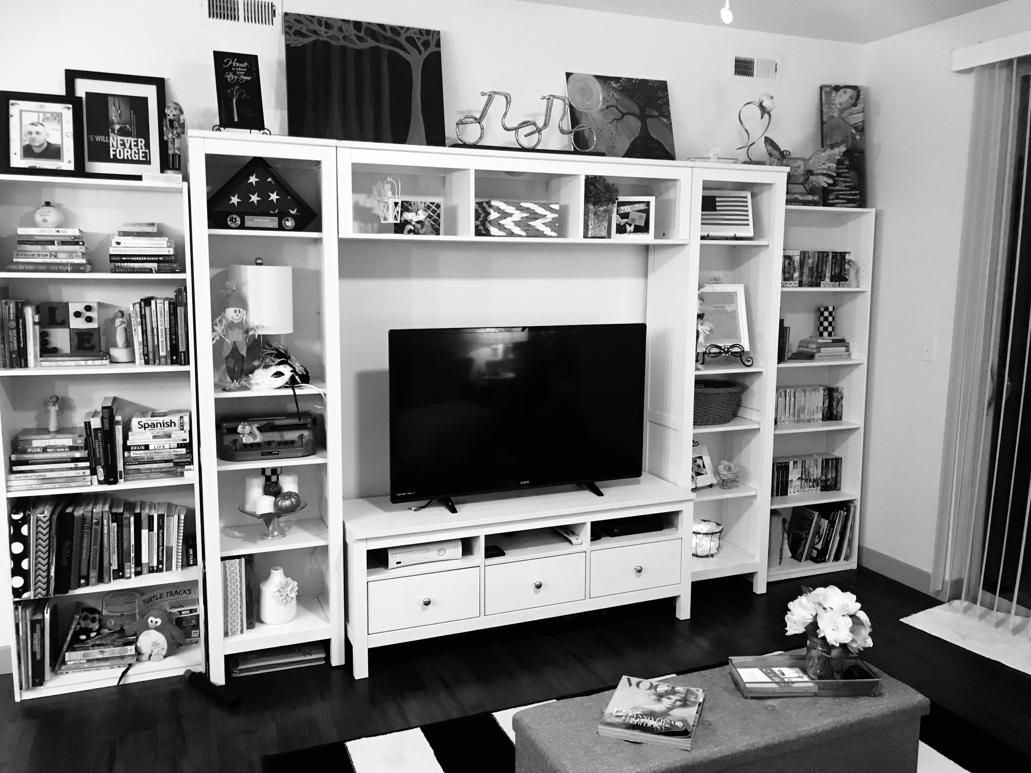 A white tv consolde with various organization and decor items, including various baskets, bins, books, photos and more. 
