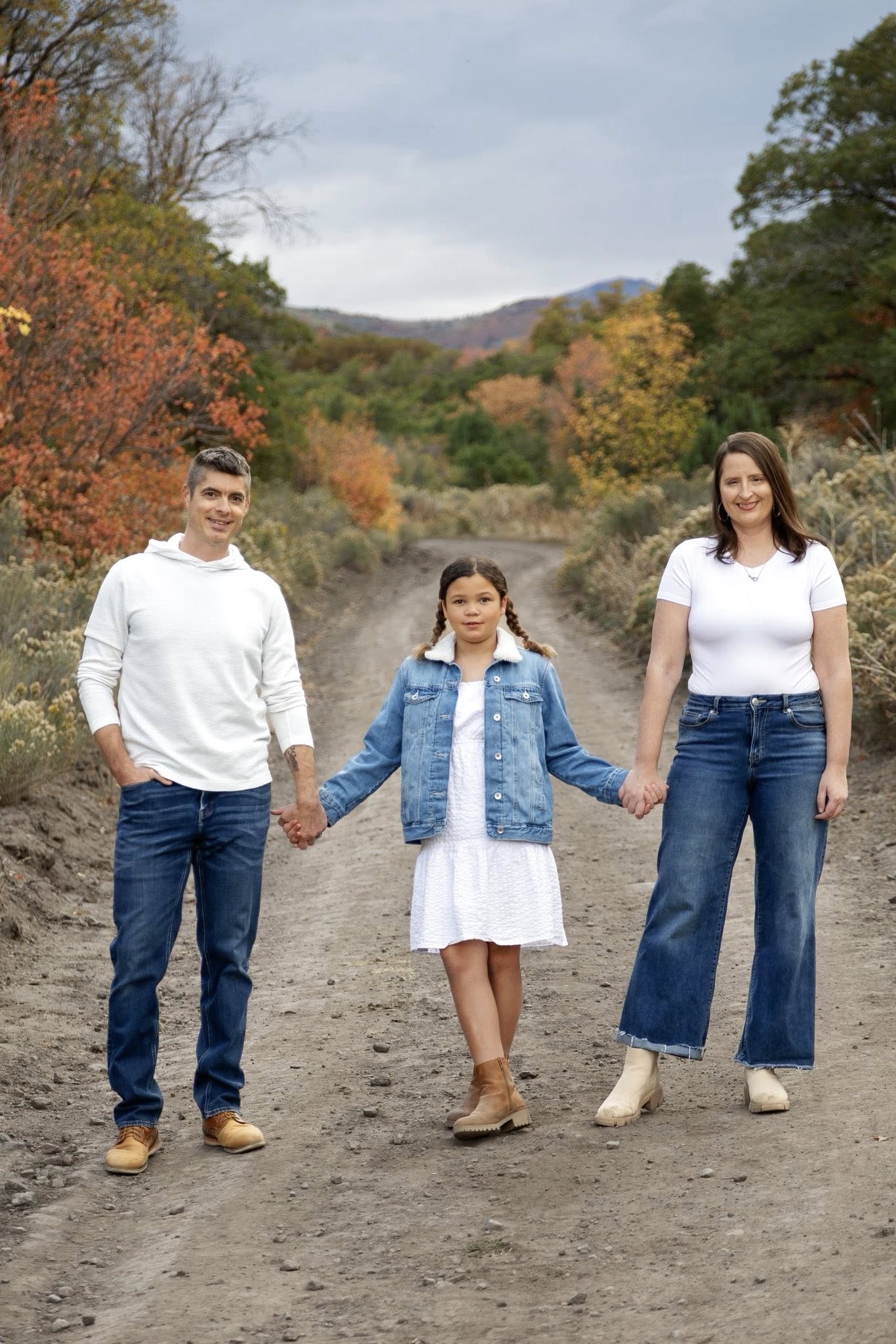 My family posing in front of fall leaves. We are holding hands and smiling.