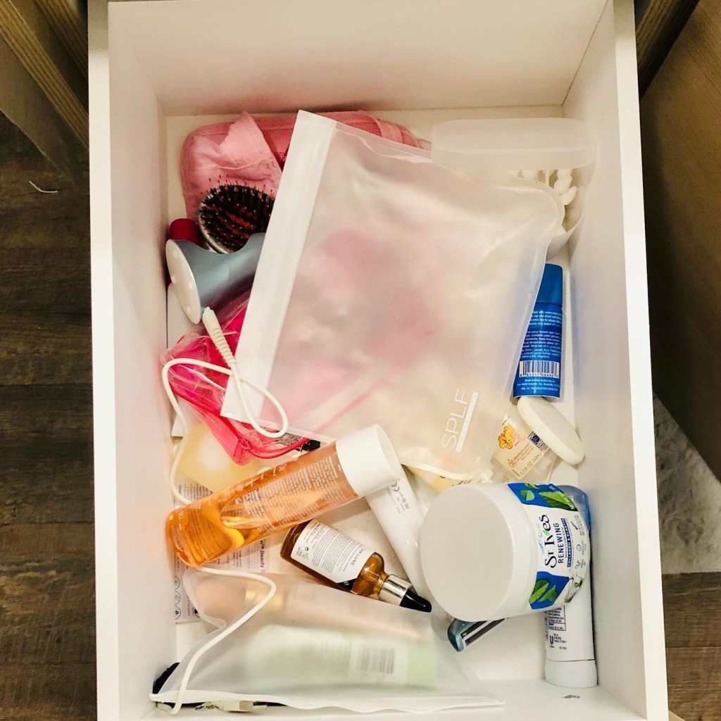A cluttered cosmetic drawer with items just stuffed in it.