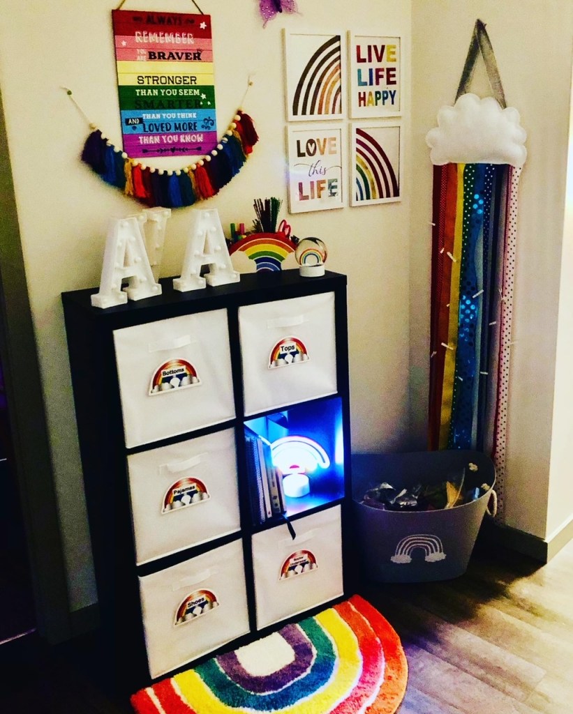 A childrens play space with rainbow touches that include labeled bins and bright, colorful art.