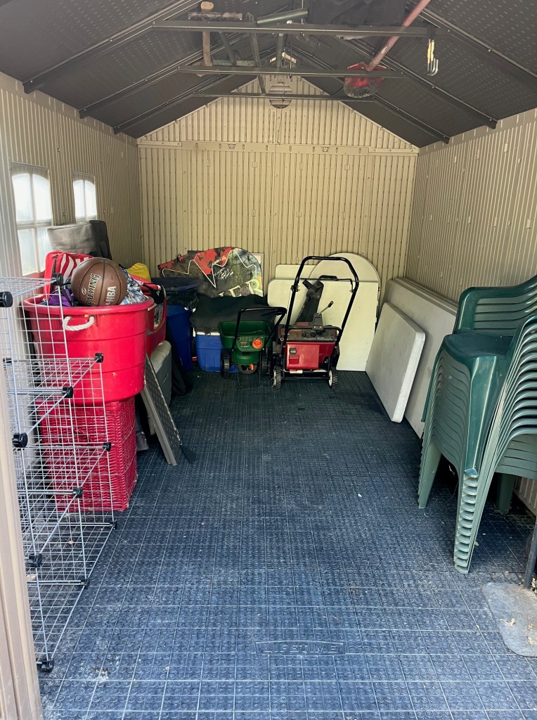A well-organized backyard shed with open room for getting items that are neatly organized on shelves. 