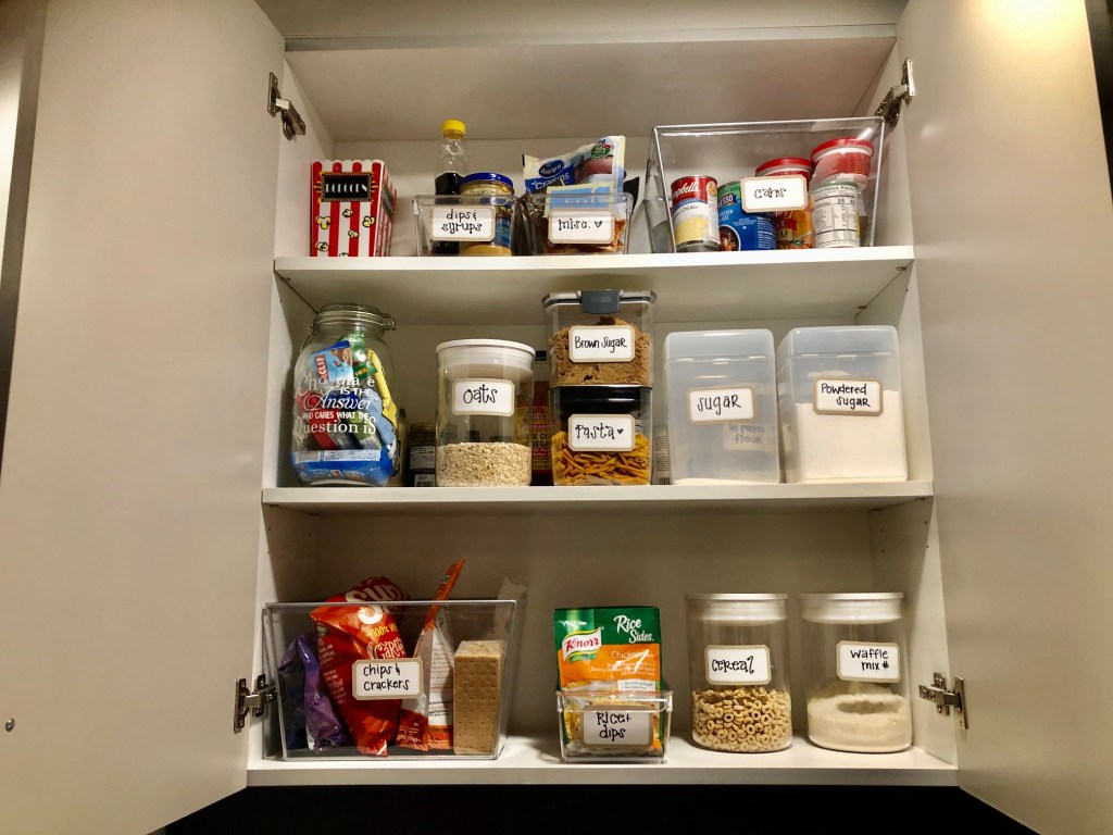 small kitchen pantry with easy-to-access clear containers with labels. 
